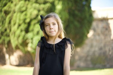 Düşüncelere dalmış düşüncelere dalmış, kaşlarını kaldırmış, dudaklarını kıvırmış, şık kıyafetler giymiş, parkta dikilmiş... 