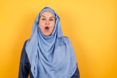 Çekici orta yaşlı tesettürlü Müslüman kadın ağzı açık, ağzı açık, ağzı açık arkadaşının hikayesini dinlerken haykırıyor: 