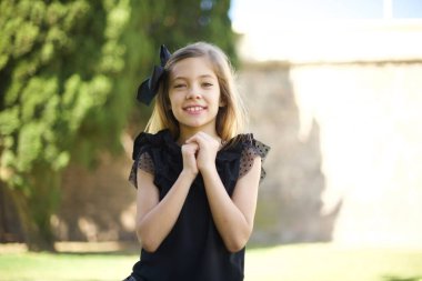 Tatlı yüzlü, rüya gibi bir genç kız. Ellerini yüzünün yanında çapraz tutuyor. Hoş bir şey için heyecanlanıyor..