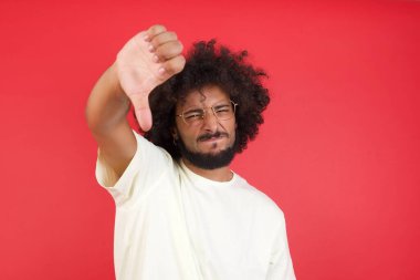 Kızıl duvarda baş parmağıyla siyah saçlı genç bir adam. 