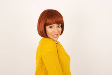 Utangaç kız kameraya bakarak gülümsüyor. Gri stüdyo geçmişine karşı kumlama yapan çekici kız utangaç hissediyor..