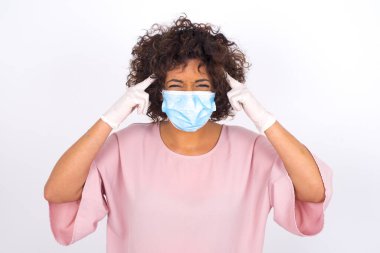 Yüz maskesi takan ve başı ağrıyan bir kadın beyaz stüdyo arka planında izole edilmiş.