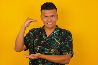 İzole edilmiş arka planda yaşayan İspanyol bir adam. Elleri büyük ve büyük bir işaret, ölçü sembolü gösteriyor. Kameraya bakıp gülümsüyor. Ölçüm konsepti.