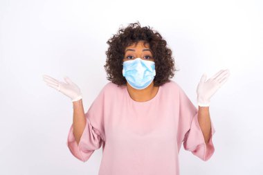 Yüz maskesi takan ve günlük kıyafet giyen kadın beyaz stüdyo arka planında izole edilmiş.