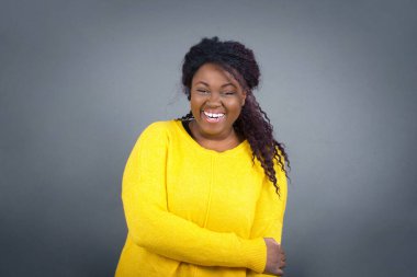 Hoş, iyi huylu, Afro-Amerikan kadın, günlük kıyafetler içinde. Sevgisini ve sempatisini göstermek için kendini tutarak büyüleyici bir gülümseme ve dostça bir ifade takınıyor. Kalbim senin için.!