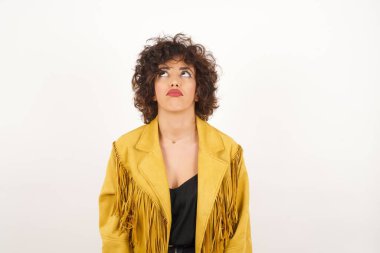 Süet ceketli güzel kadın stüdyo fotoğraflarına bakıyor.