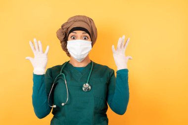 Neşeli, heyecanlı, maskeli Arap kadın doktor tezahürat yapıyor, başarıyı kutluyor, yumruklarını sıkarak evet diye bağırıyor.