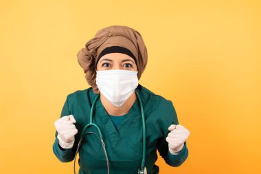 Güzel doktor kadın portresi, kameraya heyecanla bakar, ellerini başının üstüne kaldırır, beklenmedik bir şey fark eder, duvarın üzerinde izole bir şekilde.