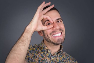 Gülümseyen, gülümseyen, el pençe divan duran, el pençe divan duran yakışıklı genç adam. Sıradan kıyafetler giyip ayakta durmak..