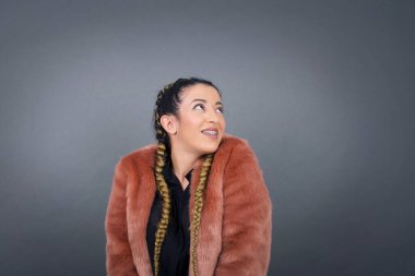 Örgü örmüş, esrarengiz bir gülümsemeyle yukarı bakan çekici bir kadının portresi. Güzel gülümseyen kız, gri duvara bakıyor..