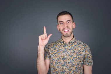 Bir parmağıyla yukarı bakıp gülümseyen, gündelik elbiseli çekici sarışın hippi bir adamın yakın plan portresi. Bir fikrim var, cevabı ya da çözümü biliyorum..