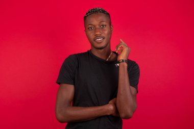 Yüzü birbirine yakın, duvarın karşısında duran neşeli, güzel, Afro-Amerikan bir adamın görüntüsü. İyi haberleri dinledikten sonra kameraya mutlu bir ifadeyle bakmak. Kendinden emin adam..