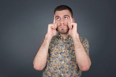 Hayalperest beyaz bir erkek, düşünceli bir yüz ifadesi var, yüzünü çevirmiş, hoş bir şeyler düşünüyor, gri duvara karşı poz veriyor..