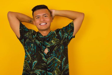 Güven ve cinsel ilişki konsepti. Çekici, genç İspanyol bir adamın portresi. Kendine güvenen bir ifadeyle gülümsüyor ve ellerini başının üstüne koyuyor. Arkaplanda duruyor.