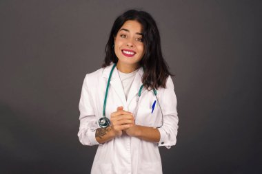 Vay canına. Güzel doktor gri stüdyo arka planında izole edilmiş. Genç, duygusal, şaşkın bir kadın, ağzı açık duruyor. İnsani duygular, yüz ifadesi kavramı. Moda renkleri.