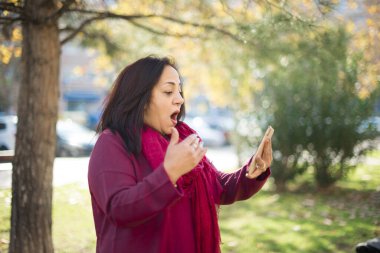 Parkta akıllı telefonu olan orta yaşlı güzel bir Arap kadın.  