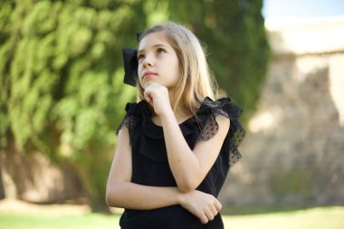 Düşünceli, gülümseyen bir kızın portresi elini çenesinin altında tutar, yan bakar, ilginç bir şey düşünür ya da merak eder, sıradan giyinir.