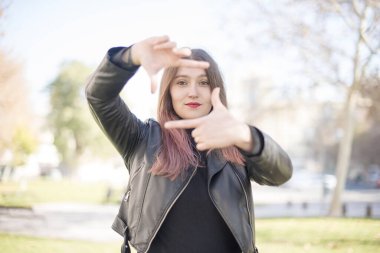 Parkta çerçevesini gösteren genç ve güzel bir kadın.