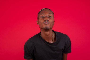 Hoş görünümlü Afro-Amerikalı bir adam dudaklarını öpecek gibi tutuyor. Mutlu bir ifadesi var, somurtkan surat. Kapalı yerde dikiliyorum. Güzellik konsepti.