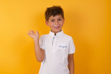 Sarı duvara yaslanmış sevimli çocuk.  