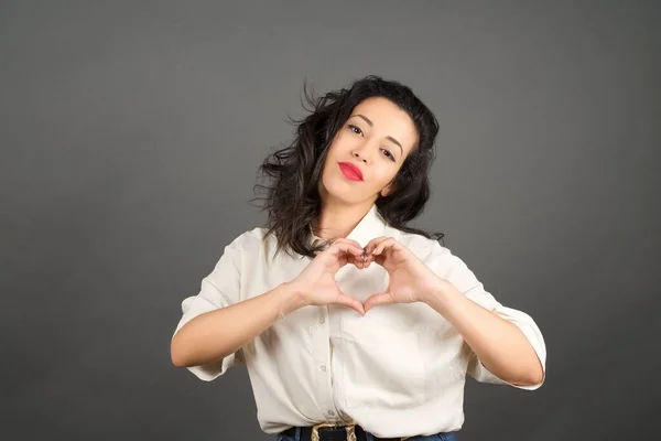 Hermosa Mujer Morena Vestida Casualmente Mostrando Corazón Pie Sobre Fondo — Foto de Stock