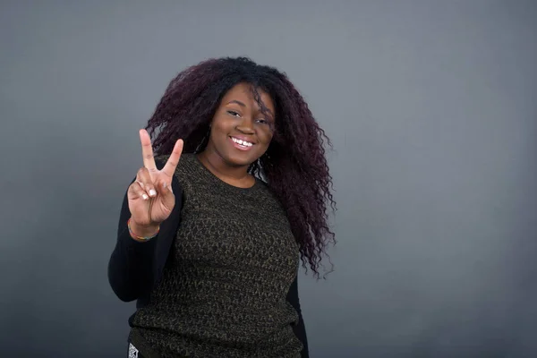 身穿休闲装的非洲裔美国女人 站在灰墙旁边 手指头数着 面带微笑 自信而快乐 — 图库照片