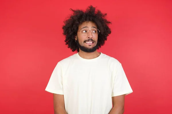 Verwirrter Junger Mann Mit Afro Haaren Blickt Gegen Rote Wand — Stockfoto