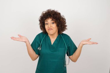 Kafası karışmış ve cahil Arap doktor kadın kollarını açmış, omuzlarını silkiyor. Negatif insan duyguları, yüz ifadeleri, yaşam algısı ve tutumu.