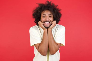 Afro saçlı genç adam kırmızı duvarda mutlu. 