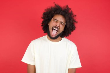 Kızıl duvarda dili olan afro saçlı genç bir adam. 