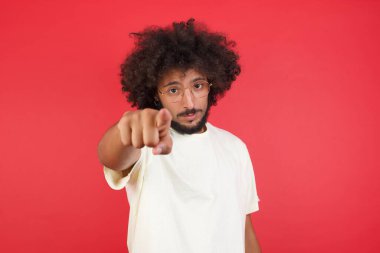 Kızıl duvarı işaret eden afro saçlı genç adam.   