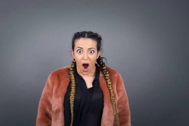 Şok olmuş genç esmer bayan, boş gri duvarda gördüklerinden sersemlemiş hissediyor.