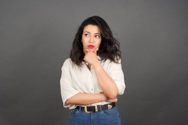 Gri arka planda gelişigüzel giyinmiş güzel esmer kadın..  