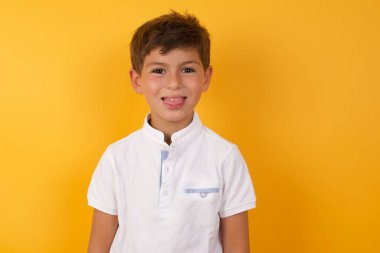 Sarı duvara dil gösteren sevimli çocuk.  