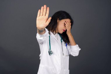 İnsanlar, vücut dili. Avrupalı genç doktor kadın avuçla gözlerini kapar ve dur hareketi yapar. Herkesten saklanmaya çalışır. Bana bakma, görmek istemiyorum, utanıyorum ya da korkuyorum..