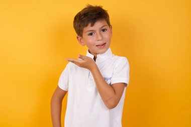 Sarı duvara bir şey gösteren sevimli çocuk.  