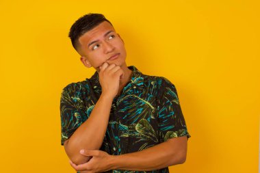 Yüz ifadeleri ve duygular. Düşünceli, gündelik giysiler içinde, kafasının altında el ele tutuşmuş, şüpheli bakışları olan genç İspanyol bir adam..