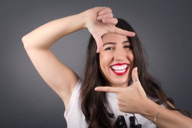 Gri arka planda çerçeve yapan güzel kadın.  