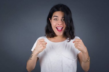 Kafkasyalı genç kadın başarısını ve zaferini kutluyor yumruklarını neşeyle sıkıyor. Hedefine ve amaçlarına ulaşmaktan mutlu olan şapkalı şanslı kadın. Pozitif duygular, duygular..