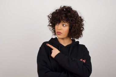 Kamerada poz veren güzel esmer kadın. İnce bakışlı ve el kol hareketi yapan..