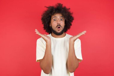 Afro saçlı genç adamın kırmızı duvara karşı kafası karışık. 