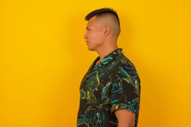 Ciddi bir adamın profili, sarı stüdyo duvarının üzerinde fotokopi alanı ile yalıtılmış bir şekilde yürümeye hazır..