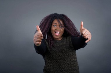 İyi iş! Mutlu gülümseyen Afro-Amerikan kadın portresi günlük giysiler içinde iki baş parmak hareketi yapıyor. Olumlu insani duygu yüz ifadesi vücut dili. Komik kız.