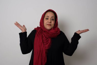 Belki evet ya da hayır. Modaya uygun, olgun Müslüman kadın şaşkınlık içinde omuz silkiyor, bir karar vermeye çalışıyor, neyi izole etmek istediğini şaşırtıyor beyaz beton duvarın üzerinden. Tereddüt ve belirsizlik.