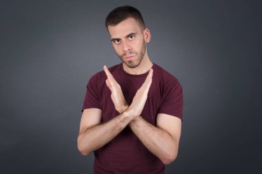 İzole edilmiş arka planda duran sıradan kıyafetler giyen genç yakışıklı bir adam. Reddedilme ifadesi olumsuz işaret göndererek el ele tutuşuyor mu?.