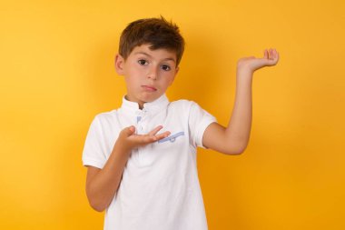 Sarı duvara bir şey gösteren sevimli çocuk.  