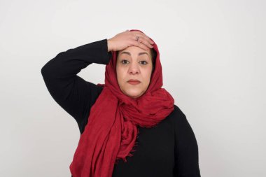 Tüh, ne yaptım ben? Olgun bir kadın, korkmuş ve pişmanlık dolu bir ifadeyle elini alnından tutuyor. Stüdyoda poz veren başörtüsü takan orta yaşlı bir Arap kadın.