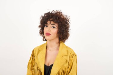 Stüdyoda, kıvırcık saçlı, sevimli bir gülümseme ile kameraya bakan güzel, genç, melez bir kadın modelin yakın çekimini yapın.