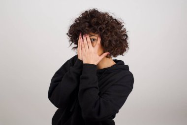 Endişe - güzel bir genç kadının kavramsal görüntüsüdür ellerini yüzünü kapatır ve bir gözü kapalı dışarı bakar. Bir şeyden ya da birinden korktun mu?.