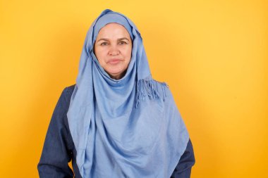 Orta yaşlı, tesettürdeki güzel Müslüman kadının beyaz boş bir kopya duvarına karşı poz verirken sevimli bir gülümsemeyle kameraya baktığı stüdyoyu kapat. 